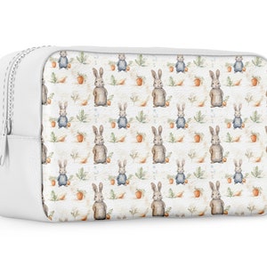 May include: White zippered cosmetic bag with a repeating pattern of watercolor bunnies and carrots on a white background.