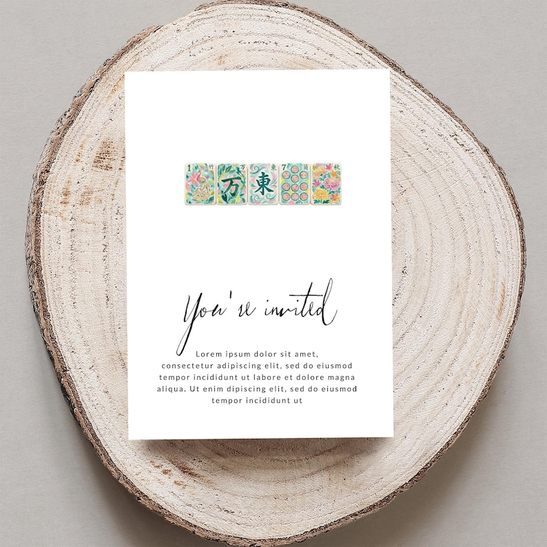 Invitation card with floral tiles and cursive text on wood slice.