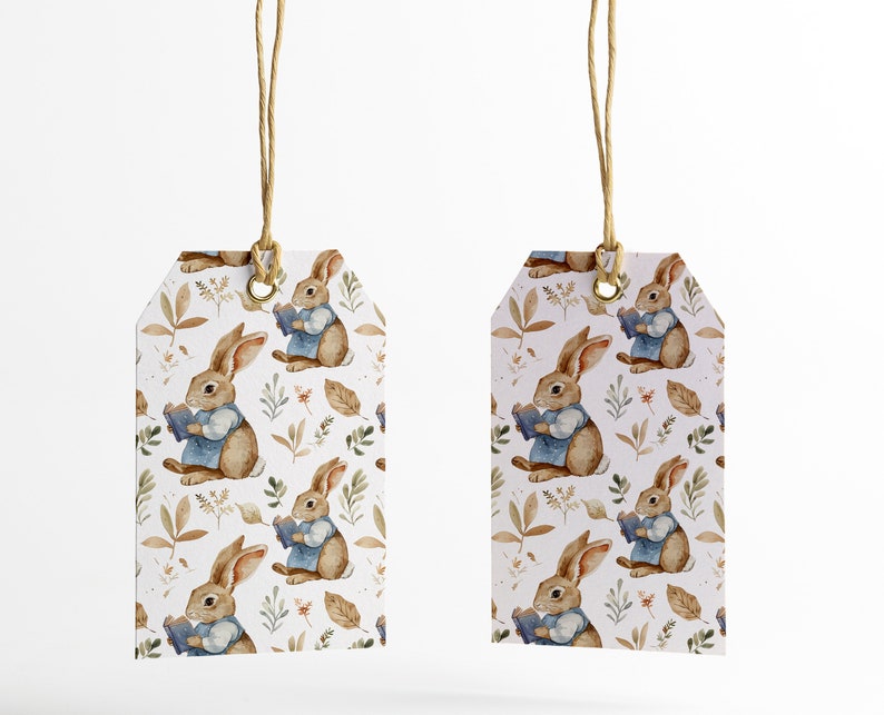 May include: Two white gift tags with brown twine hanging from the top. The tags are decorated with a repeating pattern of brown rabbits holding books, green leaves, and brown leaves.