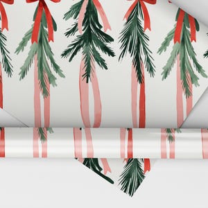K&ouml;nnte beinhalten: Wei&szlig;es Geschenkpapier mit einem sich wiederholenden Muster aus gr&uuml;nen Kiefern&auml;sten und roten und rosafarbenen B&auml;ndern. Das Papier ist aufgerollt und das Ende ist sichtbar.