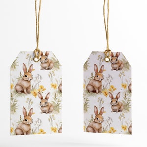 May include: Two white gift tags with brown string attached. The tags feature a repeating pattern of brown bunnies and yellow flowers on a white background.