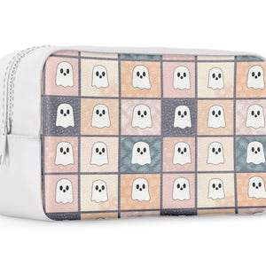 May include: White cosmetic bag with a zip closure. The bag has a colourful pattern of ghost illustrations on the front. The ghosts are white with black eyes and mouths, set against a patchwork of pastel squares.