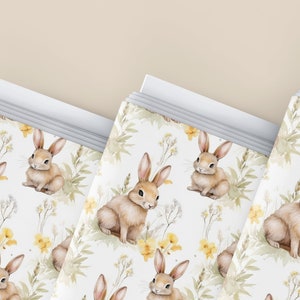 May include: A set of three white gift bags with a repeating pattern of brown bunnies and yellow flowers. The bags are stacked on top of each other.