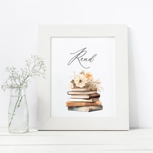 May include: A white framed print with the word "Read" in cursive script. A stack of vintage books with a floral arrangement on top is pictured below the word.