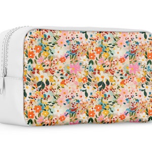 Pu&ograve; includere: Pochette bianca con cerniera e stampa floreale con una variet&agrave; di fiori colorati su sfondo bianco.