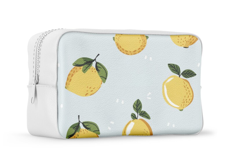 Puede incluir: Bolsa blanca con cremallera, fondo azul claro y un patr&oacute;n repetido de limones amarillos con hojas verdes.