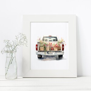 May include: A white pickup truck with the tailgate down, filled with wooden crates of pink and red flowers. The truck is on a white background.