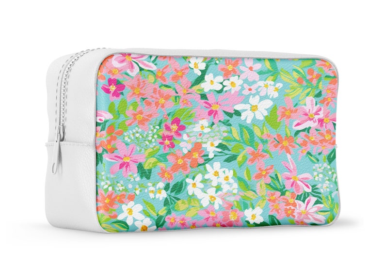 K&ouml;nnte beinhalten: Eine wei&szlig;e Rei&szlig;verschlusstasche mit einem Blumenmuster. Der Druck zeigt rosa, orange, wei&szlig;e und gr&uuml;ne Blumen auf hellblauem Hintergrund.