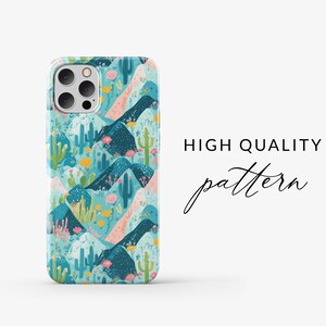 May include: A phone case with a colorful pattern of mountains, cacti, and flowers. The case is designed for an iPhone with a camera bump.