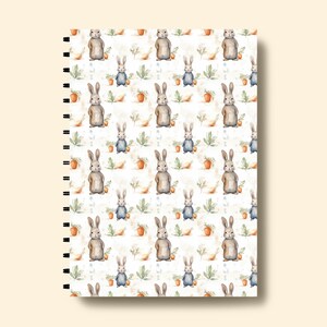May include: A white spiral bound notebook with a repeating pattern of watercolor bunnies, leaves, and carrots.