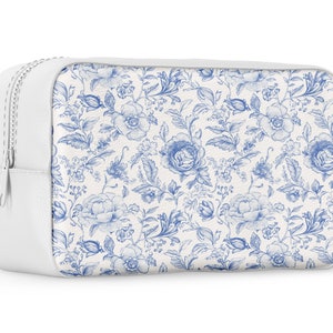 May include: White zippered pouch with a blue and white floral pattern. The pouch is made of a soft, textured material.