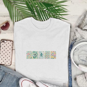 White t-shirt with floral patterned squares on chest, styled with jeans, hoodie, and headphones.