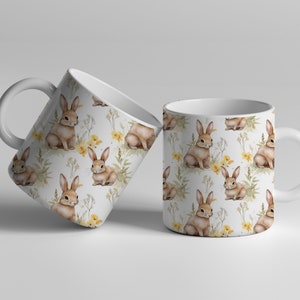 May include: Two white ceramic mugs with a repeating pattern of brown rabbits and yellow flowers on a white background.