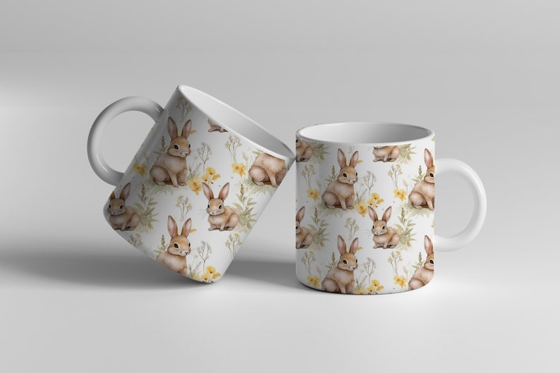 May include: Two white ceramic mugs with a repeating pattern of brown rabbits and yellow flowers on a white background.