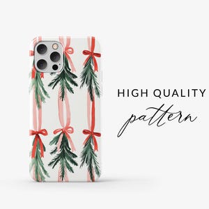 K&ouml;nnte beinhalten: Eine wei&szlig;e iPhone-H&uuml;lle mit einem weihnachtlichen Design. Die H&uuml;lle zeigt ein sich wiederholendes Muster aus gr&uuml;nen Kiefern&auml;sten mit roten Schleifen und rosa B&auml;ndern.
