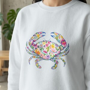 White sweatshirt with a colorful floral crab graphic.