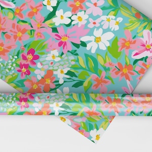 K&ouml;nnte beinhalten: Eine Rolle blaues Geschenkpapier mit einem Blumenmuster mit rosa, orange, wei&szlig;en und gr&uuml;nen Blumen.