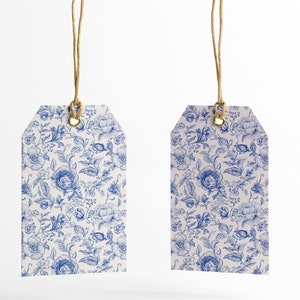 May include: Two white gift tags with blue floral patterns and gold eyelets. The tags are hanging from twine.