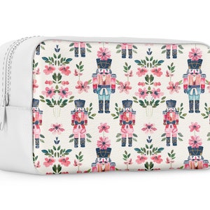 May include: White zippered pouch with a repeating pattern of pink flowers and watercolor nutcracker soldiers.