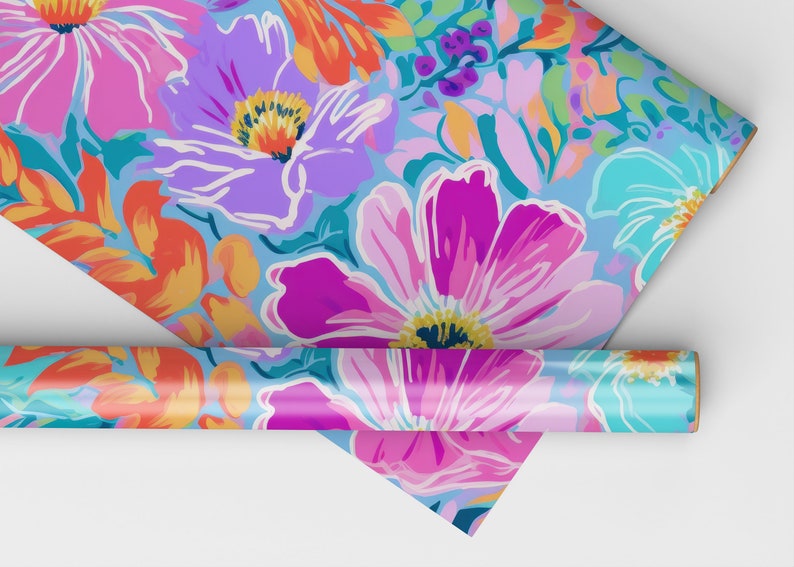 Pu&ograve; includere: Un rotolo di carta da regalo con un motivo floreale colorato. La carta presenta grandi fiori rosa, viola e blu con accenti arancioni e verdi su uno sfondo blu chiaro.