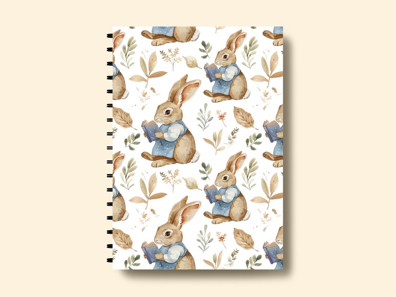 May include: A white spiral bound notebook with a repeating pattern of brown rabbits reading books, brown leaves, and green foliage.
