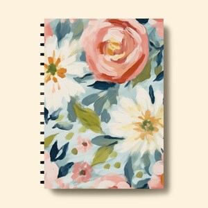 May include: A spiral bound notebook with a floral design. The cover features a colourful pattern of pink, white and blue flowers with green leaves.