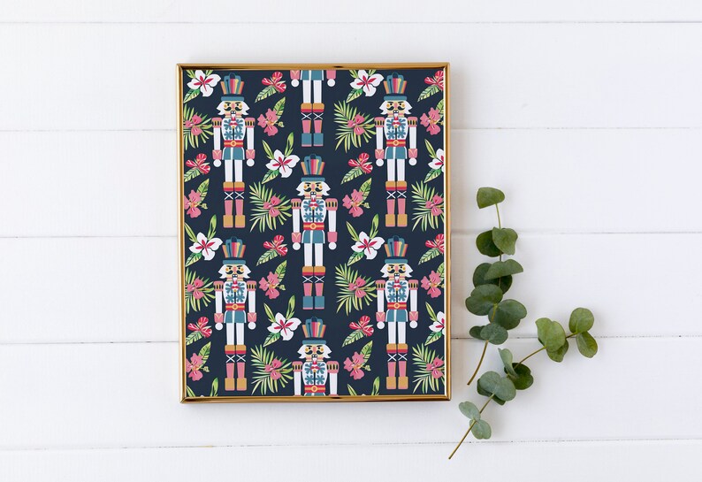 Pu&ograve; includere: Una stampa incorniciata con un motivo ripetitivo di soldati schiaccianoci e fiori tropicali su uno sfondo blu scuro. Gli schiaccianoci indossano uniformi rosse, blu e dorate e i fiori sono rosa, bianchi e verdi.