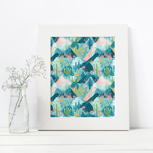 May include: A framed print with a repeating pattern of blue, pink, and green mountains, cacti, and flowers. The print has a white frame.