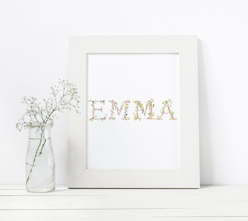 May include: White framed print with the name "EMMA" spelled out in green, pink, and white floral letters.