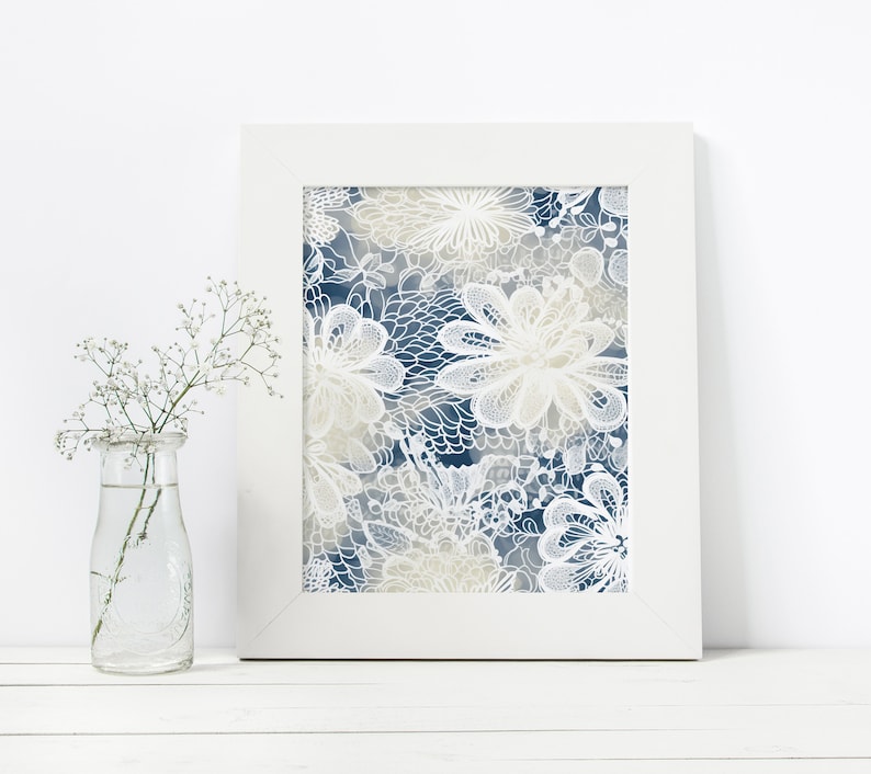 May include: A framed print featuring a white floral design on a blue background. The flowers are intricate and detailed, with soft, muted colours.