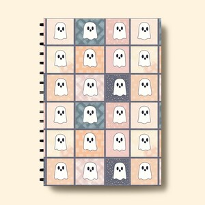 May include: A spiral-bound notebook with a repeating pattern of white ghost illustrations on a patchwork background. The squares alternate between pastel shades of peach, blue, and grey, some with a textured design.