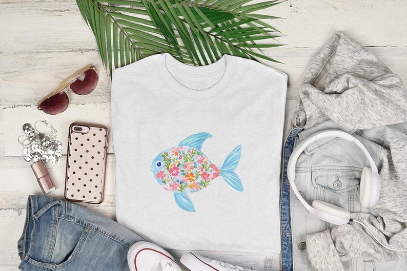 White t-shirt with a floral fish graphic, styled with jeans, headphones, and sunglasses.