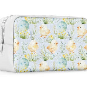 May include: White zippered cosmetic bag with a light blue background and a repeating pattern of yellow chicks and blue eggs with green foliage.