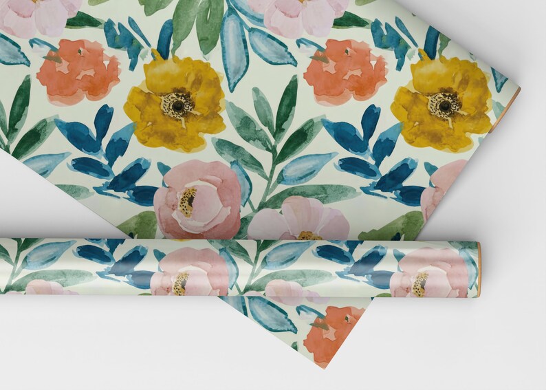 May include: Floral wrapping paper with a white background and a repeating pattern of pink, yellow, and orange flowers with blue leaves.