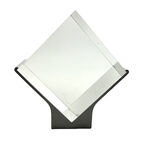 May include: A clear glass cube sits on a black metal stand. The cube is angled slightly to the right. The stand has a triangular base.