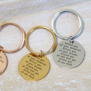 May include: Three keychains with round metal tags. Each tag has the same inscription: "Behind you, all your memories. Before you, all your dreams. Ground you, all who love you. Within you, all you need."