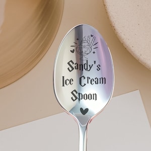 May include: A silver ice cream spoon with the text "Sandy's Ice Cream Spoon" engraved on it. The spoon has a small ice cream cone design with a cherry on top.