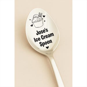 May include: A silver ice cream spoon with the text "Jose's Ice Cream Spoon" in black. The spoon features a black illustration of ice cream in a bowl with two wafer sticks. Black hearts and stars surround the illustration.