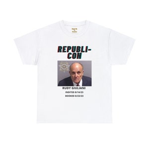 Könnte beinhalten: Weißes T-Shirt mit einer roten und blauen Grafik von Rudy Giulianis Fahndungsfoto. Der Text "REPUBLICON" befindet sich über dem Bild und "RUDY GIULIANI INDICTED 8/14/23 BOOKED 8/23/23" darunter.