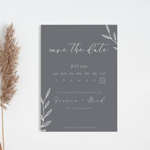 Puede incluir: Una tarjeta gris de guardar la fecha con caligrafía blanca que dice "save the date" y un calendario con la fecha 13 de julio de 2024 resaltada. El texto debajo del calendario dice "Para celebrar la boda de Jessica + Brad" y "Mt Hood, Oregón". La parte inferior de la tarjeta dice "Invitación a seguir".