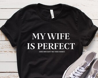 May include: Black t-shirt with white text that reads "My wife is perfect (she bought me this shirt)".