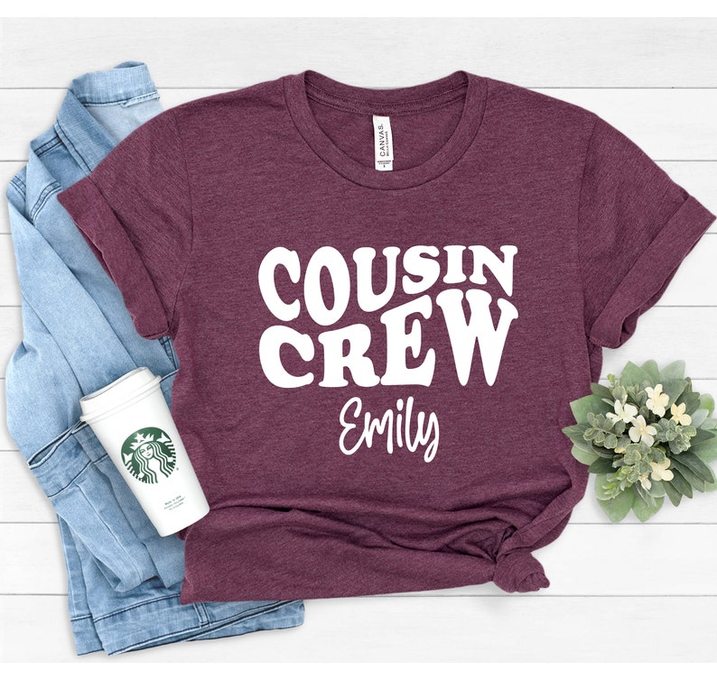 May include: A maroon t-shirt with white text that reads "COUSIN CREW Emily".