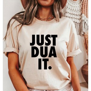 May include: A beige t-shirt with the text "JUST DUA IT." printed in black.