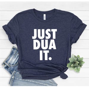 May include: A navy blue t-shirt with the text "JUST DUA IT." printed in white.