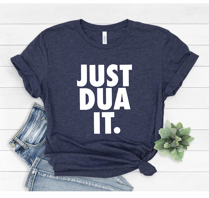 May include: A navy blue t-shirt with the text "JUST DUA IT." printed in white.