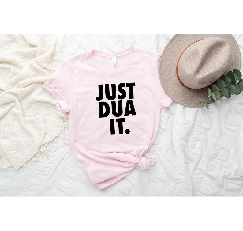 May include: Pink t-shirt with the text "JUST DUA IT." printed in black.