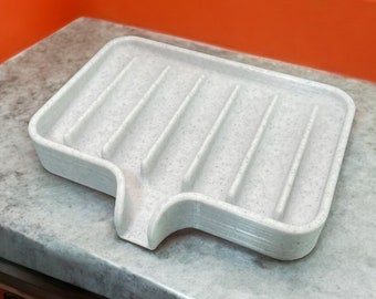 May include: A white plastic dish drying rack with a textured surface and a drain spout. The rack has multiple compartments for holding dishes.