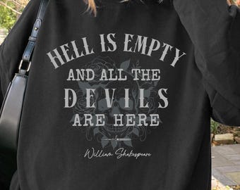 May include: Black sweatshirt with the quote "Hell is Empty and All the Devils Are Here" in gray text, attributed to William Shakespeare. The design includes a floral skull graphic. The sweatshirt is a casual style.