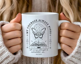 May include: White ceramic mug with a black and white design featuring a butterfly, a book, and the text "My courage always rises. At every attempt to intimidate me. Jane Austen."