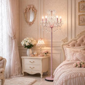 May include: A bedroom decorated in shades of pink. A crystal chandelier floor lamp stands beside a nightstand with a lamp and a vase of white flowers. A bed with a tufted headboard and floral details is visible.
